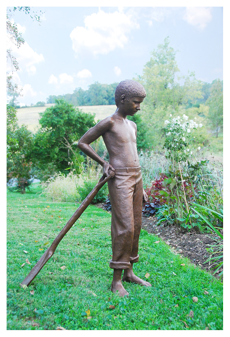 Life-size bronze sculpture of a boy with spade in a garden