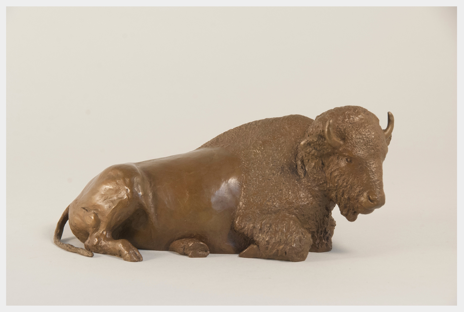 Table size bronze sculpture of a buffalo reclining