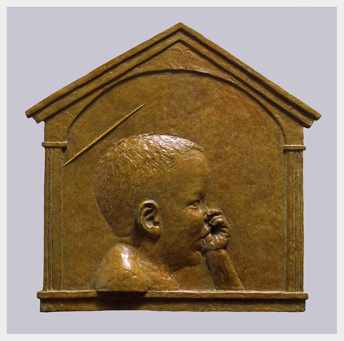 Realistic bronze bas relief sculpture of a toddler sucking his thumb with a subtle halo including framing with Renaissance architectural molding