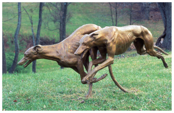 Realistic life-size bronze sculpture of two greyhounds, one in full tuck turning right and the other in full extension in midair