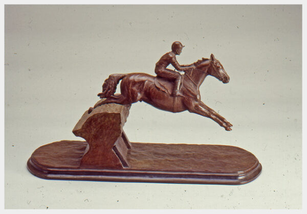 Realistic bronze sculpture of a horse with both front legs extended as it skims over a brush fence with a jockey riding.